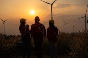 Silhouette of group engineers and windmills on the background of the setting sun photo