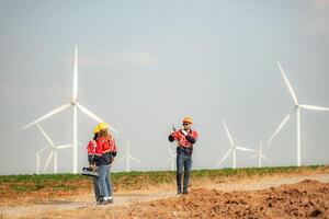 Engineer and technician greet each other in wind turbine farm with blue sky background photo