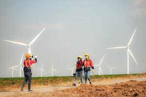 Engineer and technician greet each other in wind turbine farm with blue sky background photo