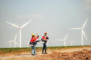 Engineer and technician greet each other in wind turbine farm with blue sky background photo