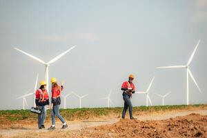 Engineer and technician greet each other in wind turbine farm with blue sky background photo
