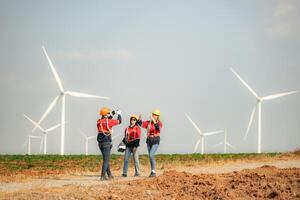 Engineer and technician greet each other in wind turbine farm with blue sky background photo