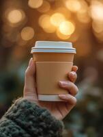 AI generated A close up of a woman's hand clasping a hot coffee cup made from recyclable paper, bathed in the gentle warmth of early morning sunlight photo