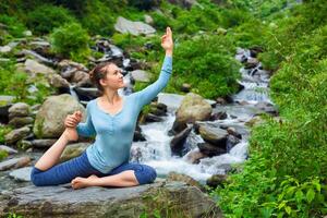 Sorty fit woman doing yoga asana outdoors at tropical waterfall photo