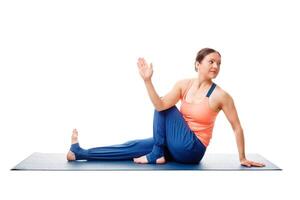 Woman doing yoga asana Ardha matsyendrasana isolated on white photo