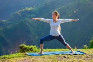 mujer haciendo yoga asana virabhadrasana 2 guerrero actitud al aire libre foto