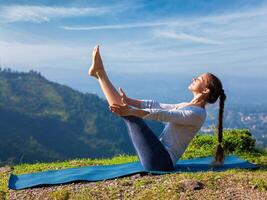 Woman doing Ashtanga Vinyasa Yoga asana Navasana   boat pose photo