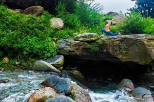 Sporty fit woman practices yoga Anjaneyasana in mountains photo