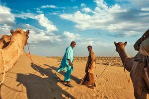 Two cameleers camel drivers with camels in dunes of Thar deser photo