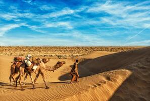 Cameleer camel driver with camels in dunes of Thar desert photo