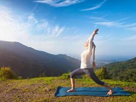 mujer haciendo yoga asana virabhadrasana 1 guerrero actitud al aire libre foto