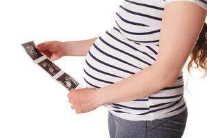 Pregnant woman standing and holding her ultrasound baby scan photo