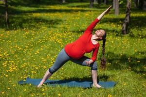 Pregnant woman doing asana Utthita parsvakonasana outdoors photo