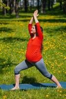 embarazada mujer haciendo asana virabhadrasana al aire libre foto