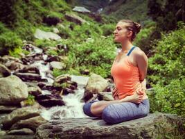 Young sporty fit woman doing yoga oudoors at tropical waterfall photo