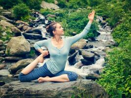 ordenado ajuste mujer haciendo yoga asana al aire libre a tropical cascada foto