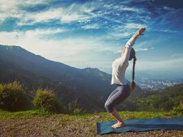 Woman doing yoga asana Utkatasana outdoors photo