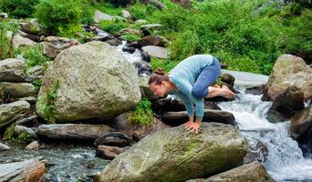 Woman doing Kakasana asana arm balance outdoors photo