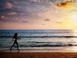 Beautiful athletic woman running along sea beach in the morning photo