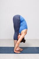 Woman doing yoga asana Uttanasana   standing forward bend photo