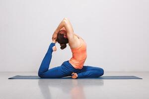 mujer haciendo hatha yoga asana eka pada rajakapotasana foto