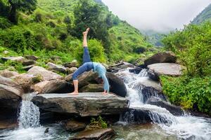 Woman doing yoga asana at waterfall photo