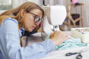 Beautiful young woman sewing clothes using a sewing machine photo