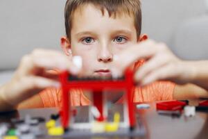 Boy Intently Assembling a Red Toy Building Set photo