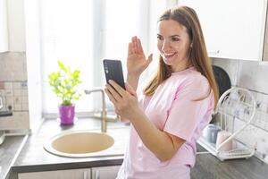 Woman Video Calling on Smartphone in Kitchen photo