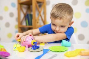 Cute child sitting at the table and plays with playdough photo