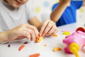 Cute children sitting at the table and plays with playdough photo