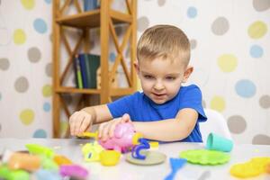 Cute child sitting at the table and plays with playdough photo