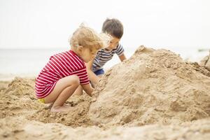 Two little boys playing on sandy beach. Cute kids building sandcastles on beach photo