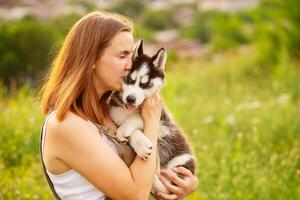 Woman playing with cute little husky puppy dog outdoors. Pet and owner love photo