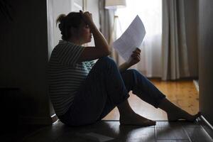 Silhouette of a sad woman sitting on the floor of her apartment photo