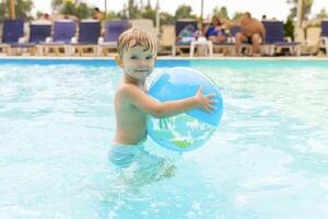 niño nadar, bucear, ocio y jugando inflable pelota en piscina a vacaciones foto