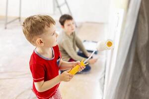 Children paint a wall with brush and roller in white color. Children paint wall photo