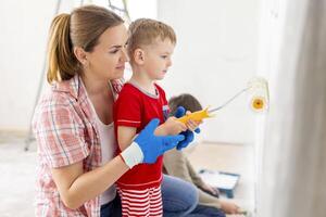 madre con su niños pintura el pared con pintar utilizando rodillo y cepillo foto