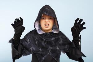 Portrait of an angry little boy in a wizard costume on a blue background photo