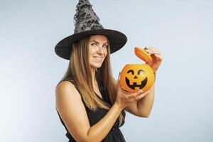 Happy young woman in halloween witch costume with pumpkin basket jack-o-lantern photo