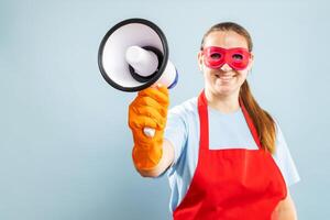 Woman in red mask, gloves and apron with megaphone on blue background photo