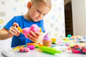 Cute children sitting at the table and plays with playdough photo