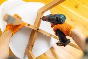 Assemble furniture. Man assembling chair. Furniture assembler with drill photo