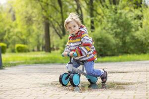 Active blond boy riding balance bike or run bike outdoor park photo