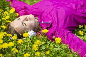 hermosa joven mujer en auriculares escucha a música acostado en el césped foto