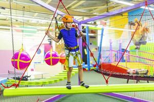 Boy in protective gear holding safety rope and passing obstacle course photo