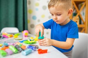 Cute children sitting at the table and plays with playdough photo