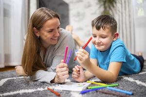 Happy family playing together on floor. Mother and son painting together photo