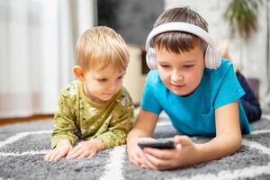 dos niños acecho inteligente teléfono, contento niños utilizando teléfonos inteligentes juntos foto