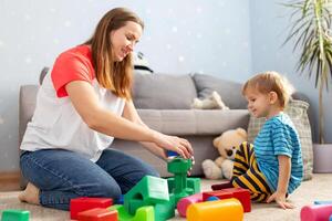 Kid and child development specialist playing together with colorful blocks photo